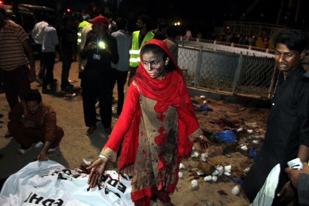 A Pakistani woman stands with blood on her hands next to a body at the blast site in eastern Pakistan's Lahore, March 27, 2016 (Xinhua)
